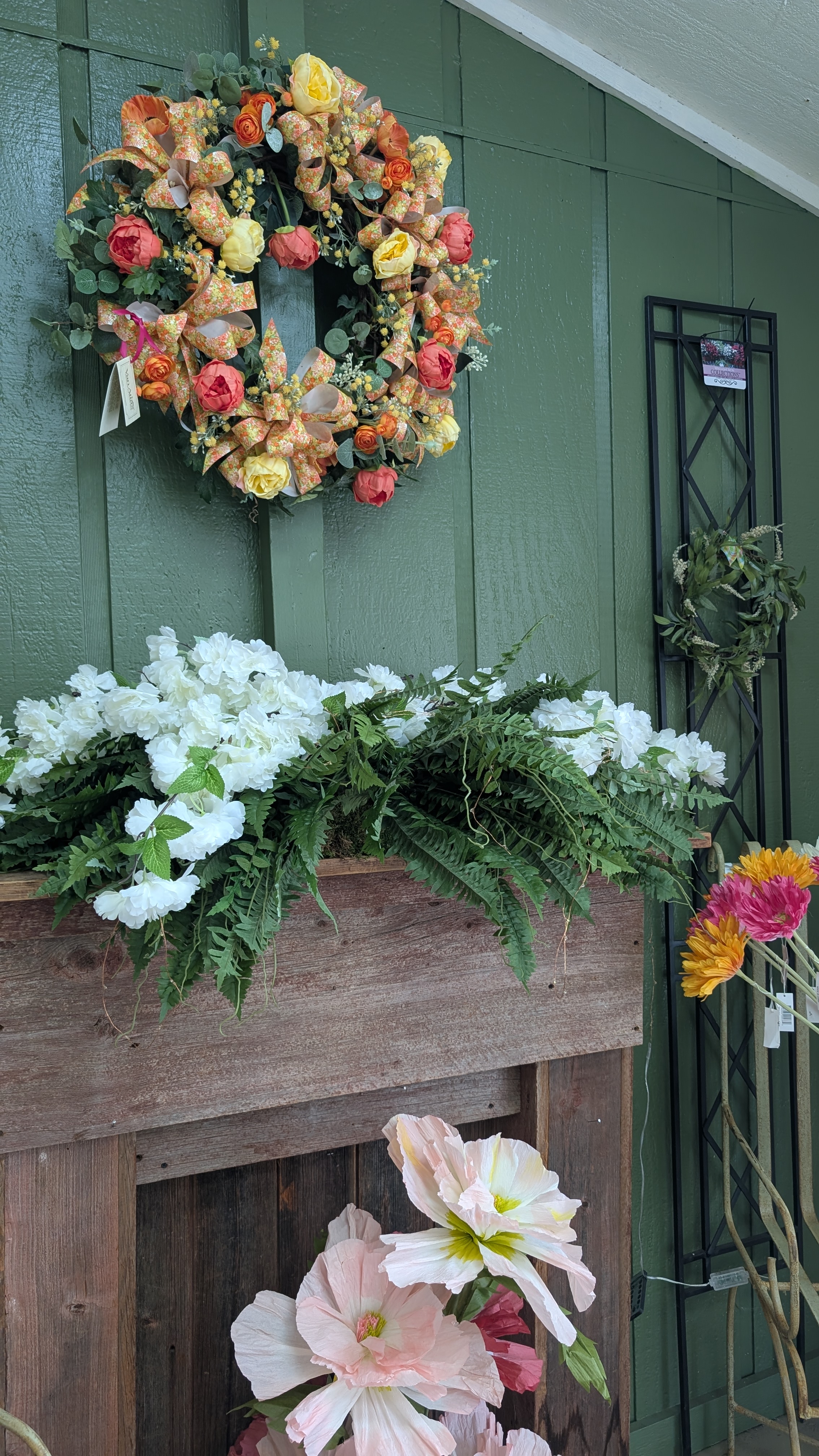 Green wall with a mantle. There is a wreath above the mantle and a white flower arrangement on the mantle.