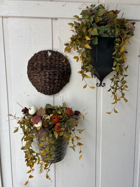 Three different wall sconces/holders, two of which have fall themed silk flowers.