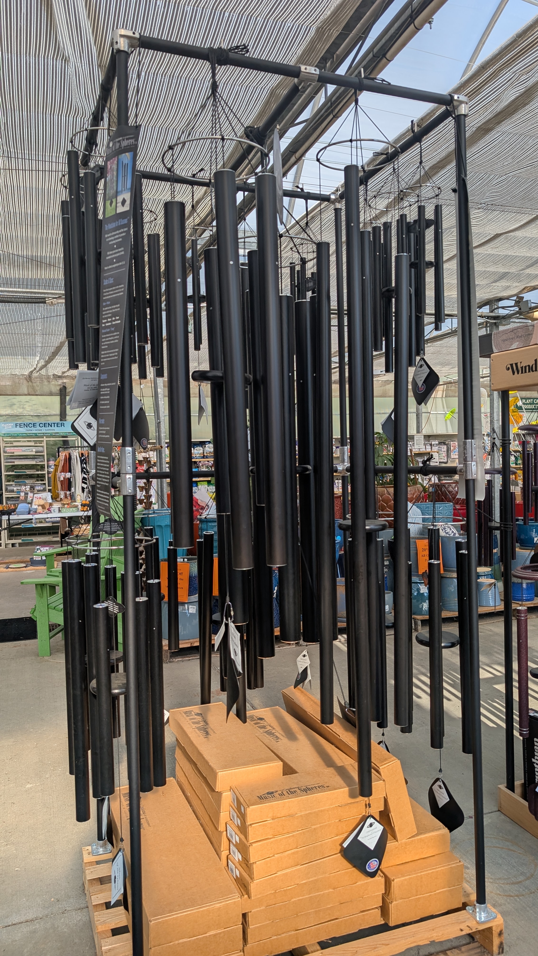 Black windchimes of different sizes hanging from a metal display rack.