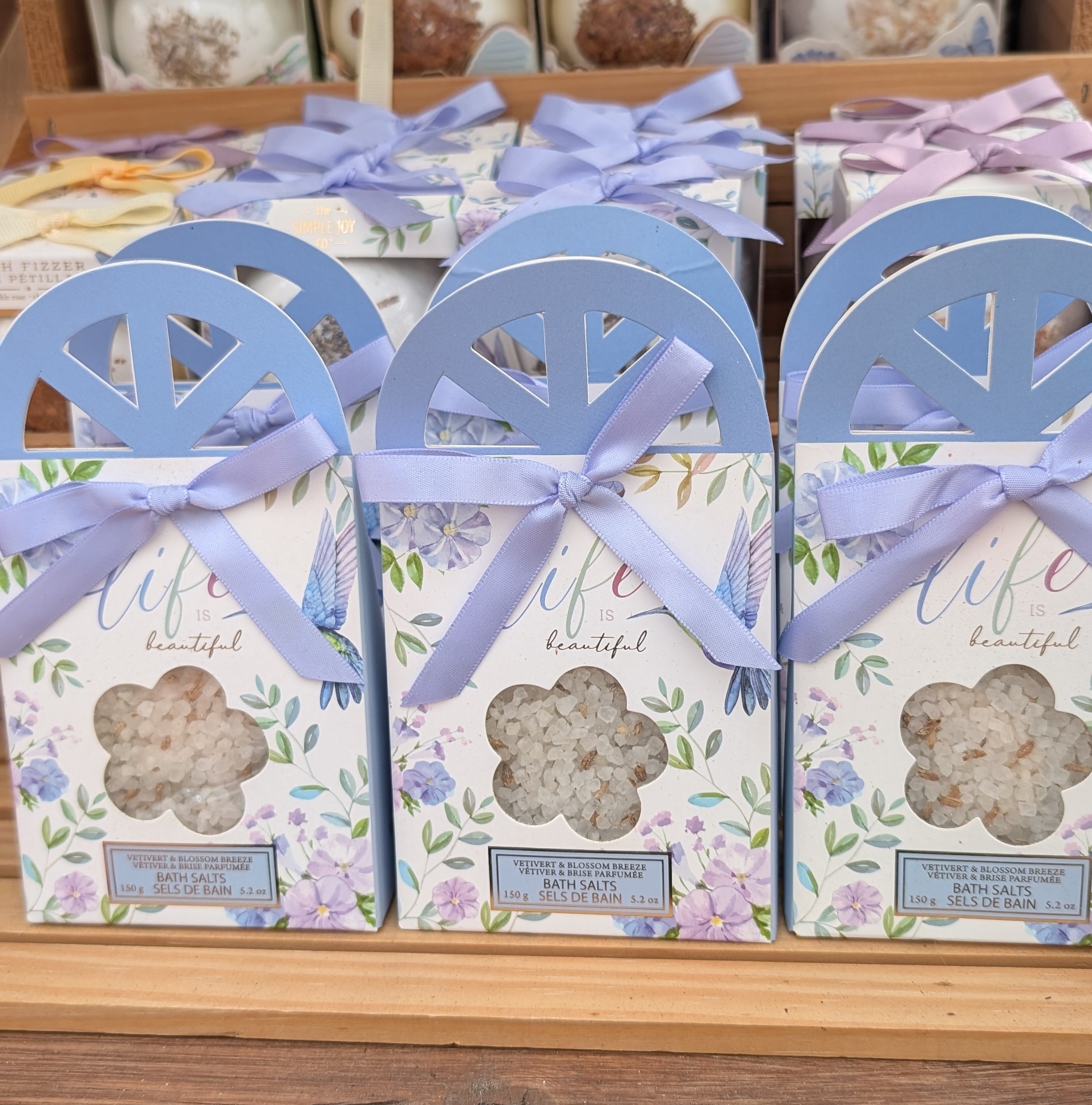 Display of packaged bath bombs and bath salt with pastel ribbons.