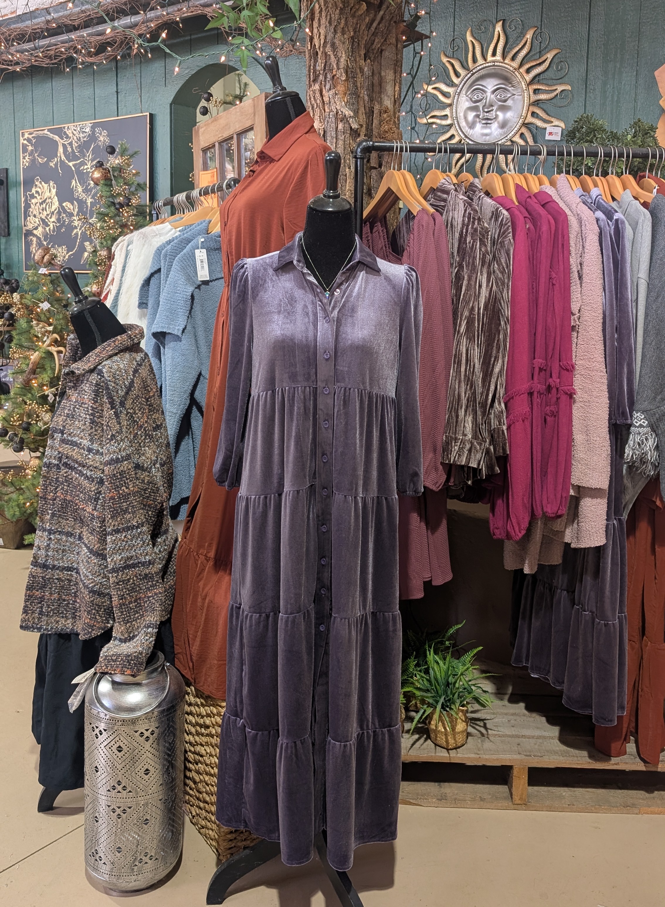 Display of fall and winter clothing with a tree and sun icon in the background.