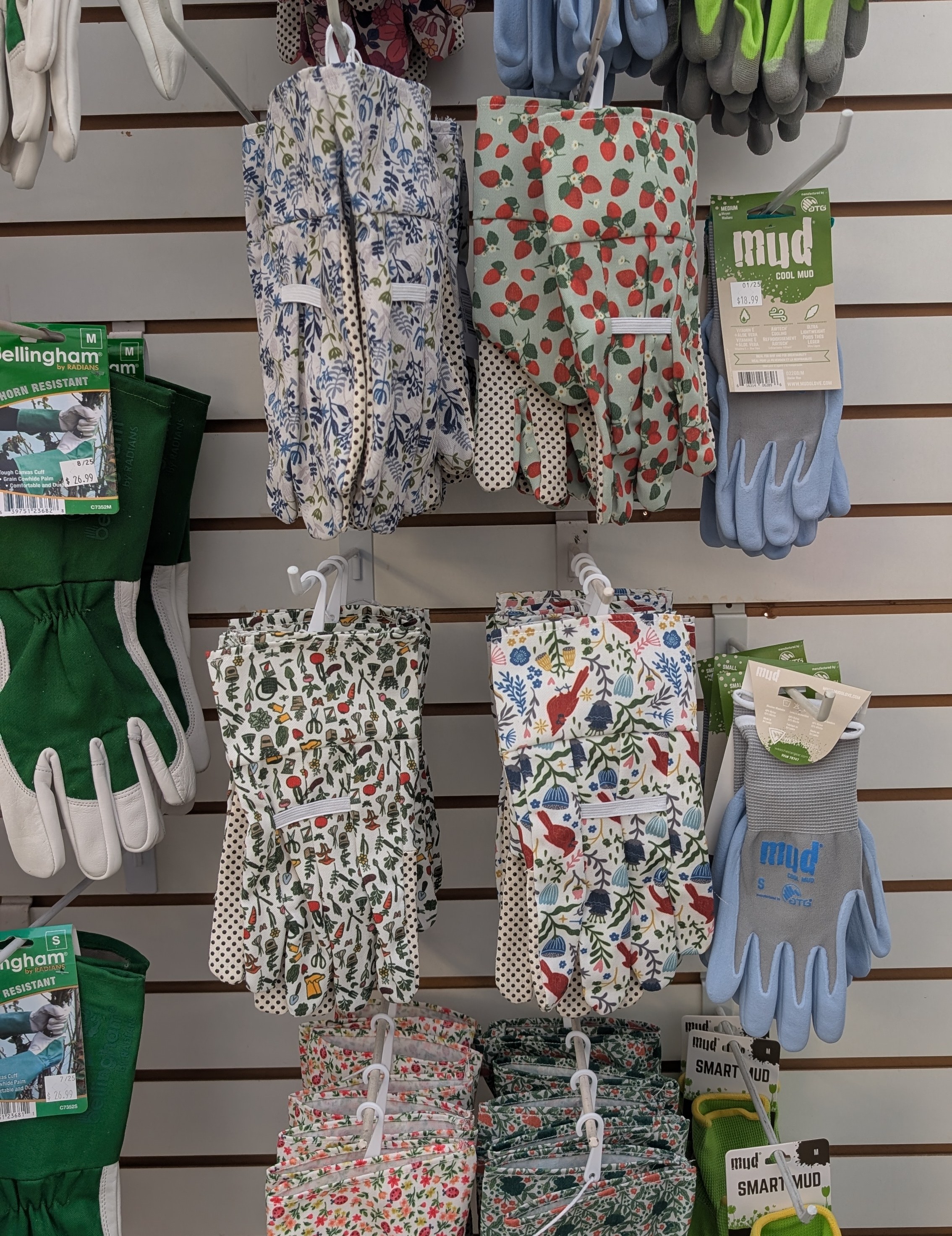 Colorful garden gloves hanging on a slat wall.