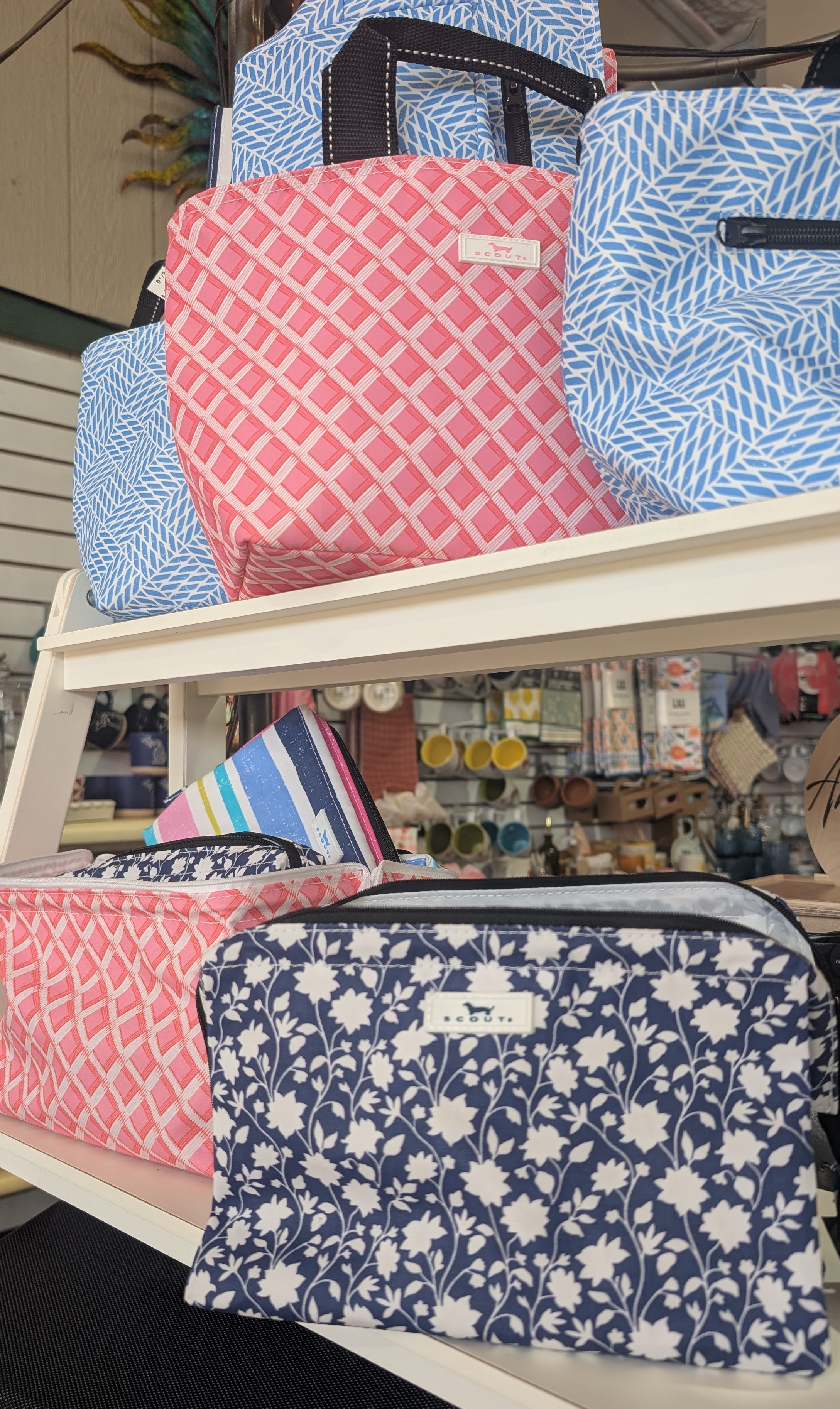 White shelf with blue and pink Scout brand bags.