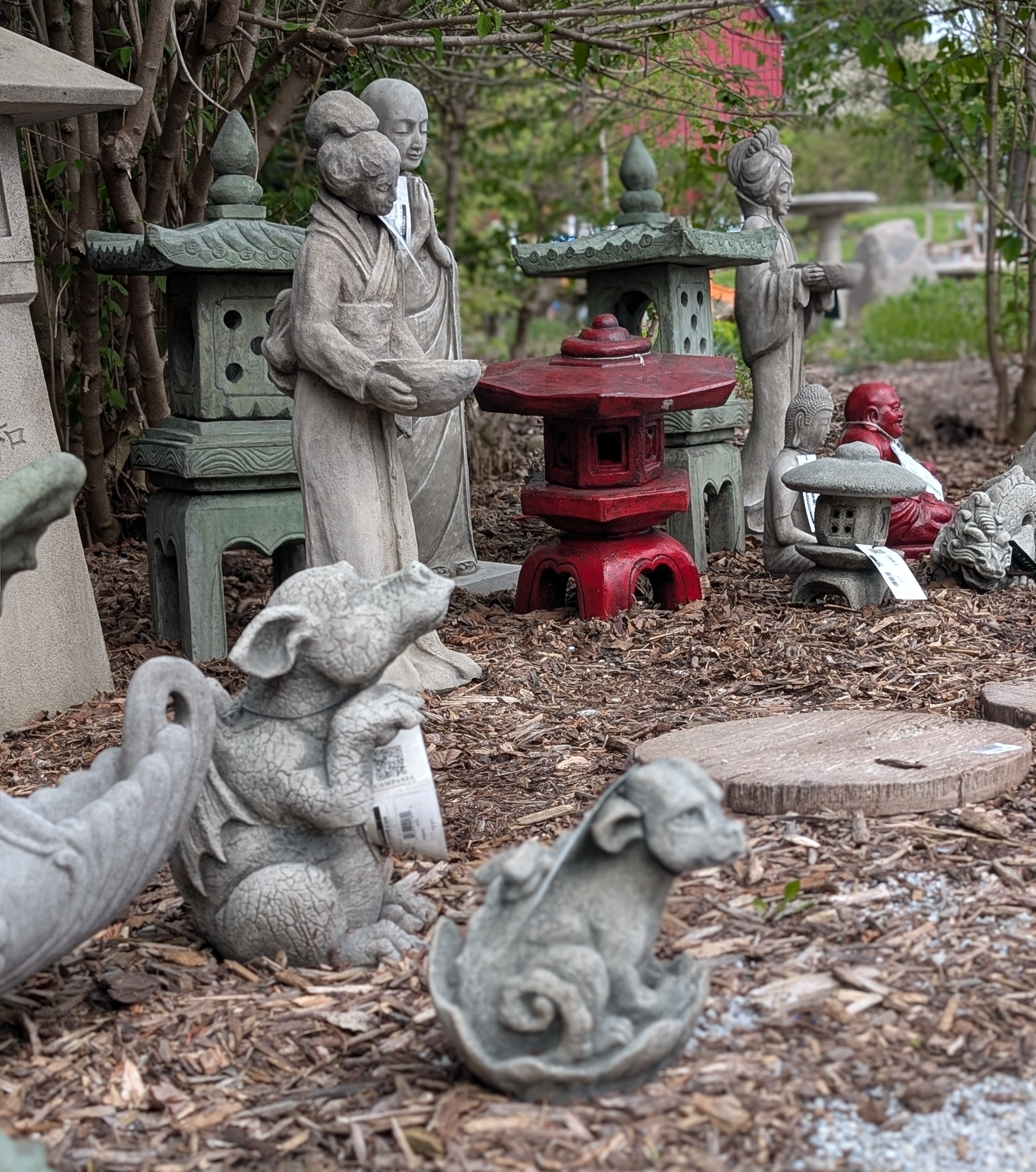 Concrete statues of dragons, standing people, and pagodas in a garden setting.