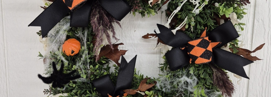 Wreath with orange and black ribbon and small jack-o-lanterns on a white background.